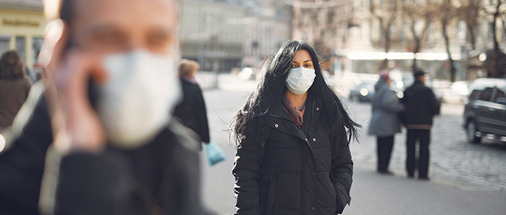 Frau mit Mund-Nasen-Schutz in Fußgängerzone