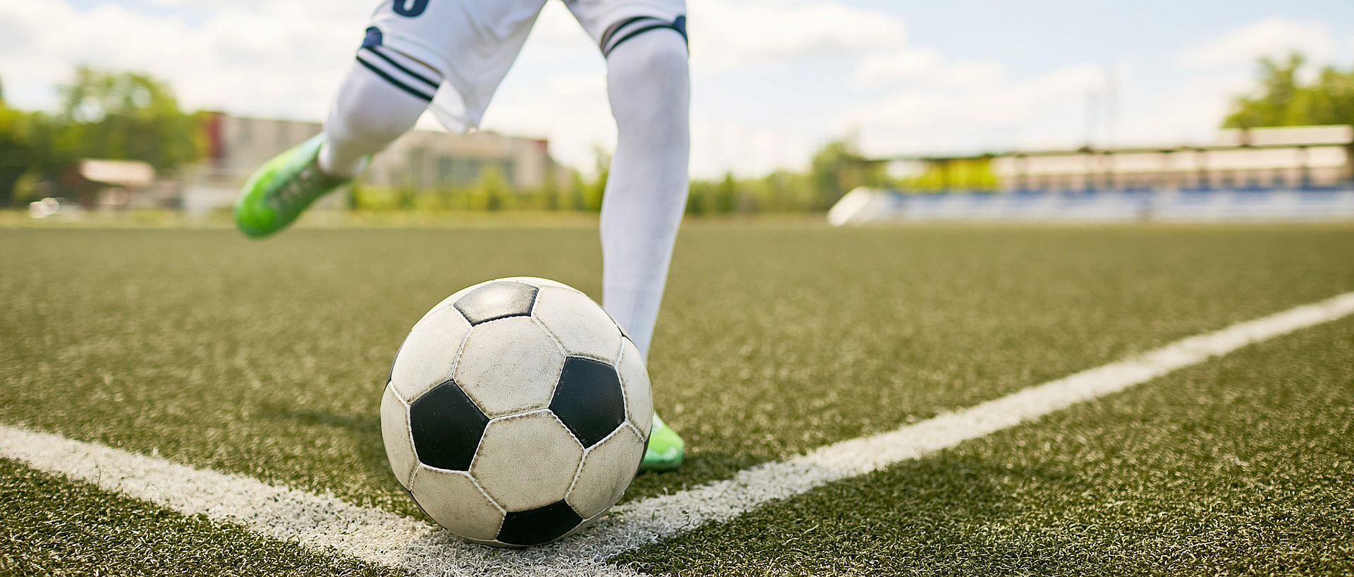 Ein Fußballspieler ist kurz davor einen Eckball zu schießen. Zu sehen sind nur Ball und Beine des Spielers.