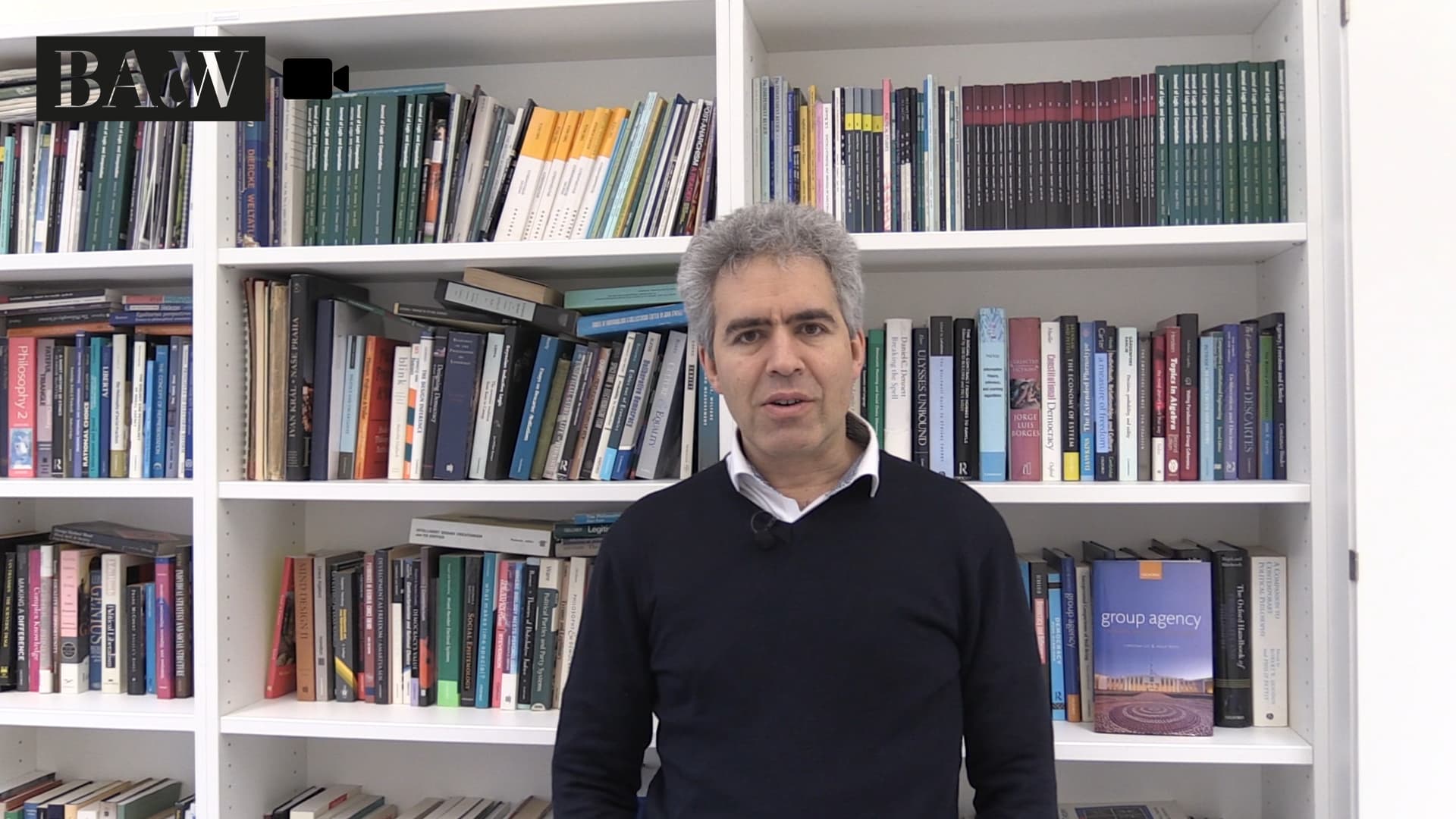 Christian List vor seinem Bücherregal